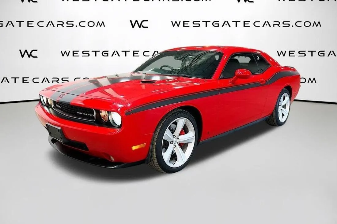 Red Dodge Challenger in a dealer photo covered by a website watermark, before AutoLander